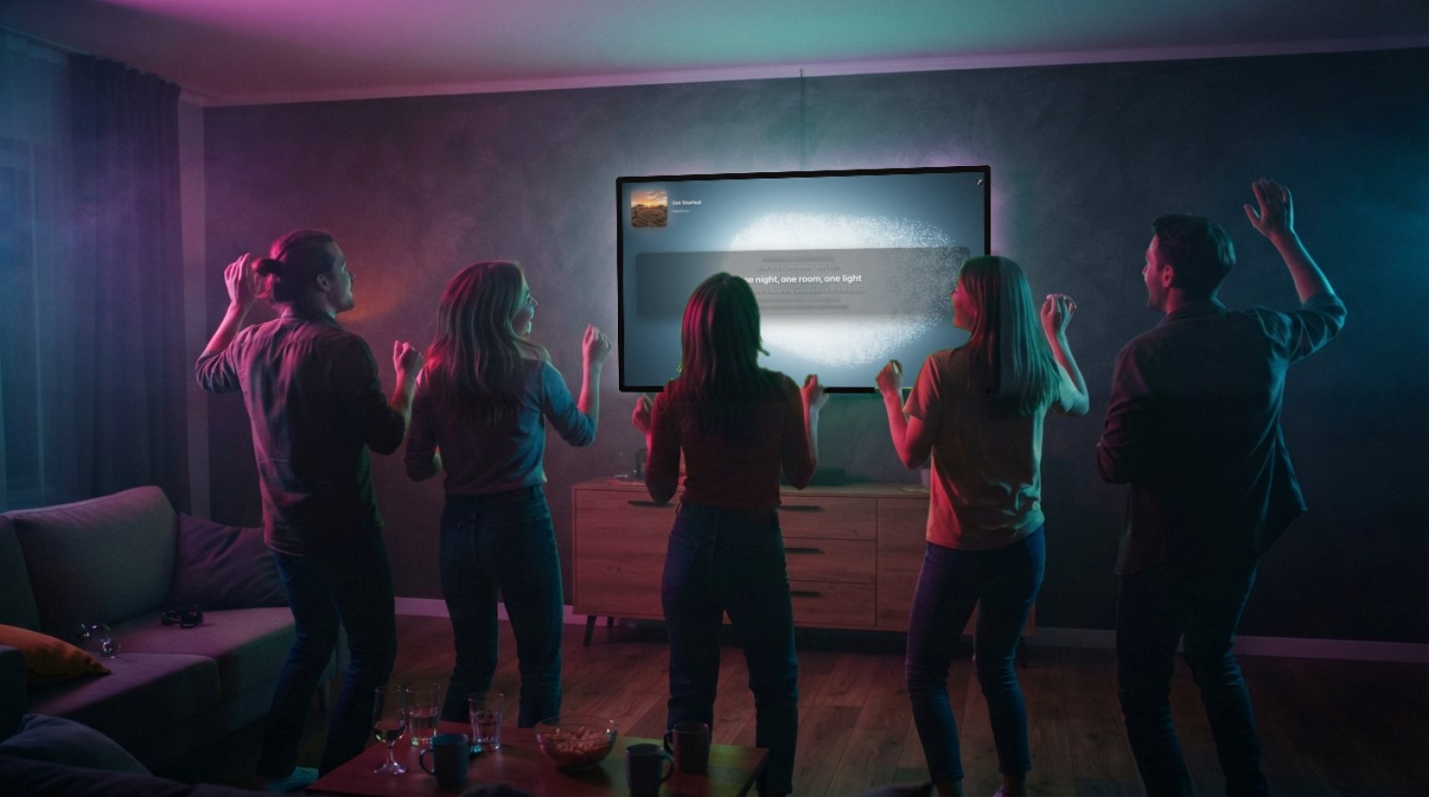 Five friends dance with their backs to the camera in front of the living-room TV, which shows a song's synced lyrics in the Halofloor karaoke box.