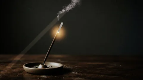 Incense : Incense stick with smoke rising through a beam of light